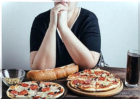 An anxious woman over two pizzas and a cola cola. 
